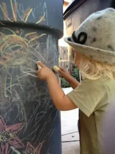 Sydney drawing with chalk on our trash can in the back yard